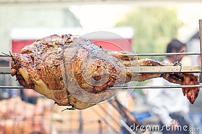 Appetizing grilled pork on the spit. Roasted leg of porkon traditional barbecue. Prepared of a ram pig baked pork meat Street food Stock Photo