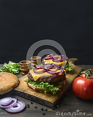 Appetizing homemade burgers with a juicy beef chop, red onion, cheese, salad and tomatoes, on vintage cutting board, close up, Stock Photo