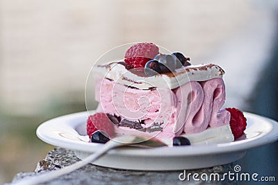 Appetizing pink and white ice cream with chocolate and berries of raspberries and black currant on a plate for dessert. Stock Photo