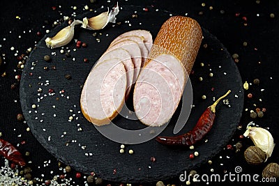 Appetizing sausage sliced on a slate board on a black background with spices and chilli selective artistic focus Stock Photo