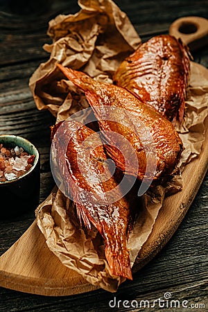 Appetizing smoked fish. Hot smoked river bass fish on a wooden background. vertical image. top view. place for text Stock Photo