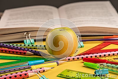 Apple, book and colorful school stationery items on a yellow background. Concept back to school Stock Photo