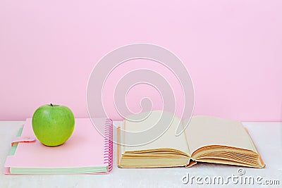 Apple, book, copybook on the desk on pink background Stock Photo