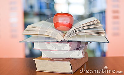 An apple on the books on the table with bookshelf in the library bookshelves background - Education learning concept open book Stock Photo