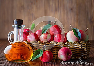 Apple cider vinegar in a glass bottle. Apples in a wicker basket. Stock Photo