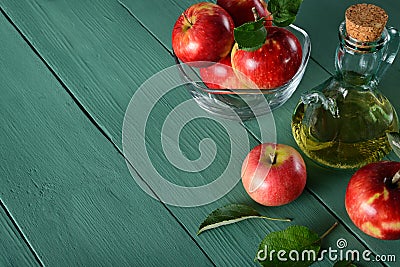 Apple cider vinegar and ripe red apples on background of green w Stock Photo