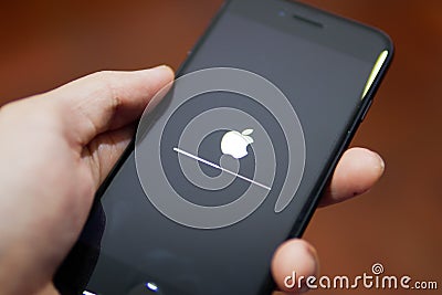 Apple iPhone 7 showing its screen with Apple logo when it is being updated the software to iOS 12 Editorial Stock Photo