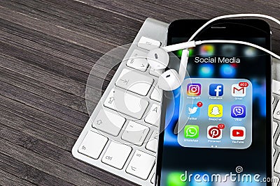 Apple iPhone 7 on wooden table with icons of social media facebook, instagram, twitter, snapchat application on screen. Smartphone Editorial Stock Photo