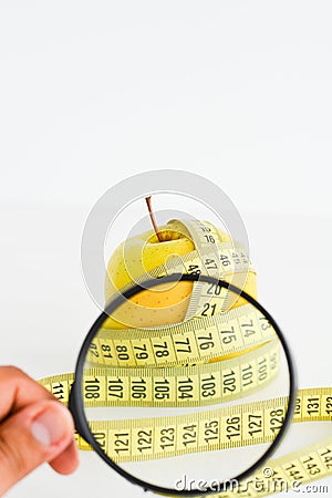 Apple, measuring tape and magnifying glass suggesting diet results Stock Photo
