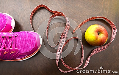 apple, meter tape, pink sneakers. Fitness accessories. Stock Photo