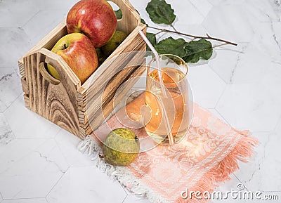 Apple and pear juice in a glass glass, apples in a wooden box on a light background. Stock Photo