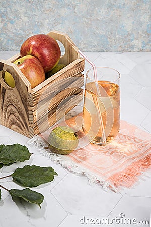 Apple and pear juice in a glass glass, apples in a wooden box on a light background. Stock Photo