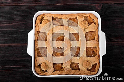 Apple pie in a square ceramic baking sheet on a dark wooden background Stock Photo