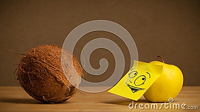 Apple with post-it note looking curiously at coconut Stock Photo