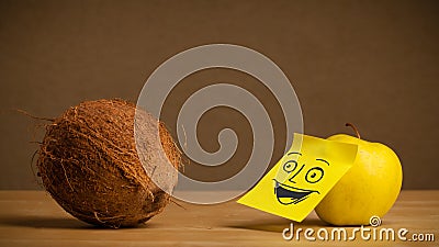 Apple with post-it note smiling at coconut Stock Photo
