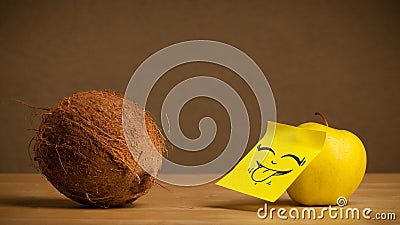 Apple with post-it note sticking out tongue to coconut Stock Photo