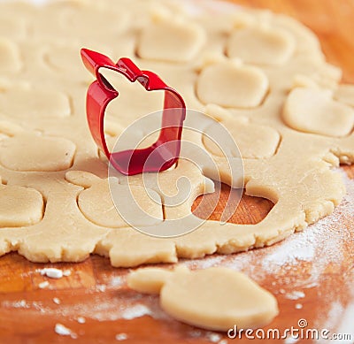 Apple shaped cookie cutter on raw cookie dough. Stock Photo