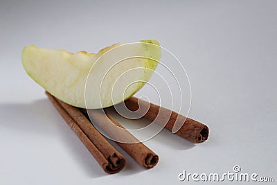 Apple slice a piece of Apple lies on three sticks of cinnamon on a white background Stock Photo