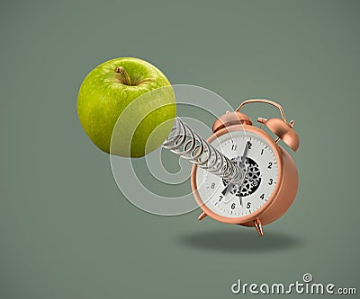 Apple on spring coming out of alarm clock Stock Photo