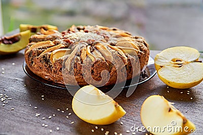 Apple tart with quince, poppy seeds, raisins and sesame on wooden brown table. Apple pie decorated with sliced fresh quince, apple Stock Photo