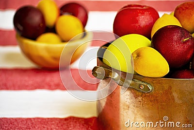 Apples, prunes and apricots in old copper pot and wooden bowl on the background Stock Photo