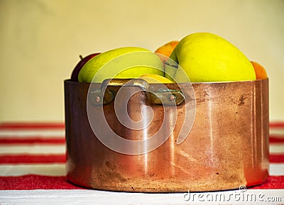 Apples, prunes and apricots in old copper pot and wooden bowl on the background Stock Photo