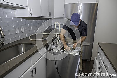 Appliance repairman working on a dishwasher Stock Photo