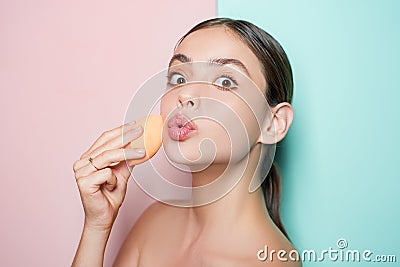 Apply concealer and cosmetic highlighter. Girl hold cosmetic applicator. Woman spreading cream on her face. Skin cream Stock Photo