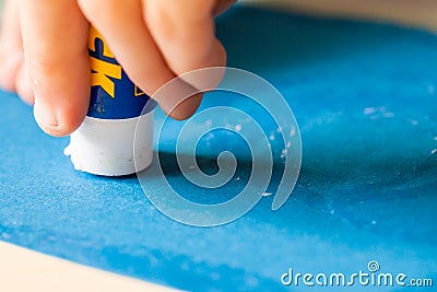 Applying glue stick to the blue paper Stock Photo