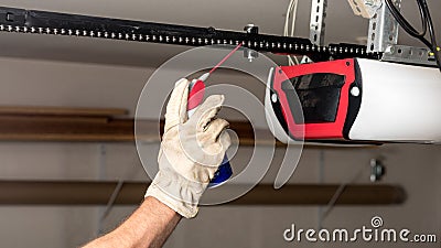 Applying oil to a chain of a garage door opener Stock Photo