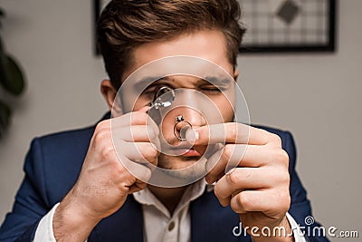 Appraiser with magnifying glass examining jewelry Stock Photo