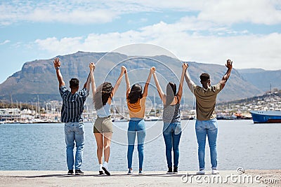 Appreciate the friends you make along your journey. Rearview shot of a group of friends holding their hands up while Stock Photo