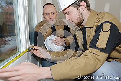 Apprentice construction man using tape measurer at site Stock Photo