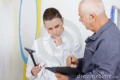 Apprentice decorator holding scraper with senior mentor Stock Photo