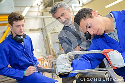 Apprentice learning to use bow saw Stock Photo