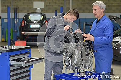 Apprentice mechanic in auto shop working on car engine Stock Photo