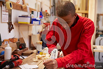 Apprentice Planing Wood In Carpentry Workshop Stock Photo