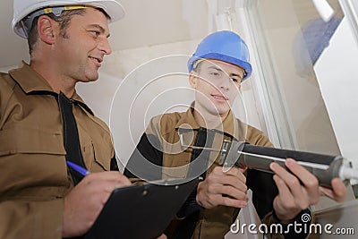 Apprentice renewing silicone joint on window Stock Photo