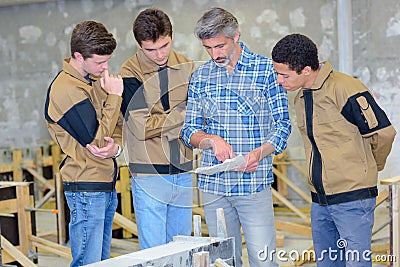 Apprentices reading plans held by instructor Stock Photo