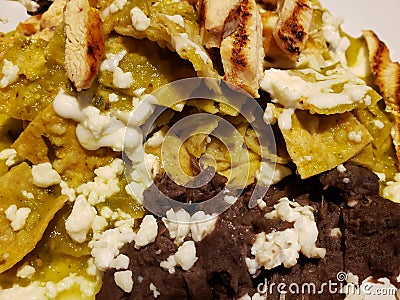 approach to plate of chilaquiles in green sauce with strips of roasted chicken and refried beans, traditional mexican food Stock Photo