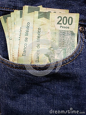 approach to front pocket of jeans in blue with Mexican banknotes Stock Photo