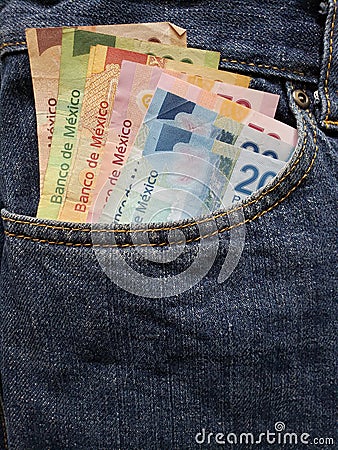 approach to front pocket of jeans in blue with Mexican banknotes Stock Photo