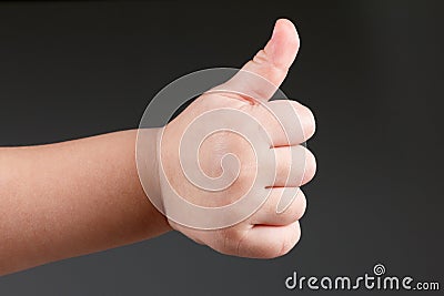 Approval thumbs up like sign, child hand gesture over dark background Stock Photo