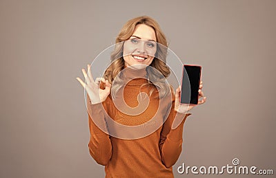 Approved mobile phone. Happy girl show OK sign to smartphone. Approved concept Stock Photo