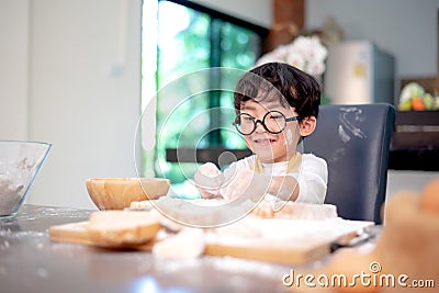 Appy Asian kid helping mom for cooking. Preparing an ingredient with powder and flour. Stock Photo