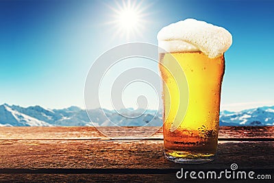 apres ski - cold beer glass on the table with sunny winter mountains landscape at ski resort Stock Photo
