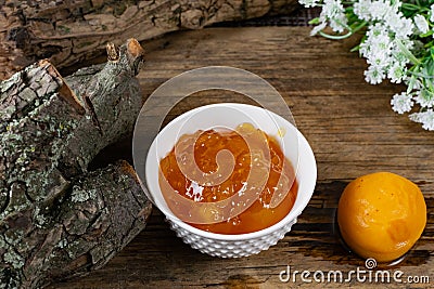 Apricot and peach jam in a small deep dish, sweet orange jam for dessert. Next to a whole fruit, apricots are marinated in syrup. Stock Photo