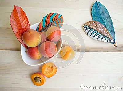 Apricots in white bowl with hand painted leavesl Stock Photo