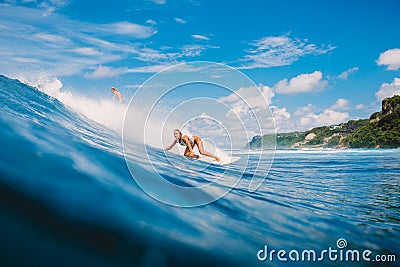 April 04, 2021. Bali, Indonesia. Sporty young woman in tropical ocean during surfing. Surfer girl on surfboard and perfect wave Editorial Stock Photo