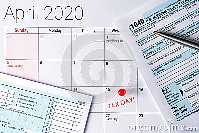 April 2020 calendar with the 15th pinned with tax day text, and 1040 tax forms Editorial Stock Photo